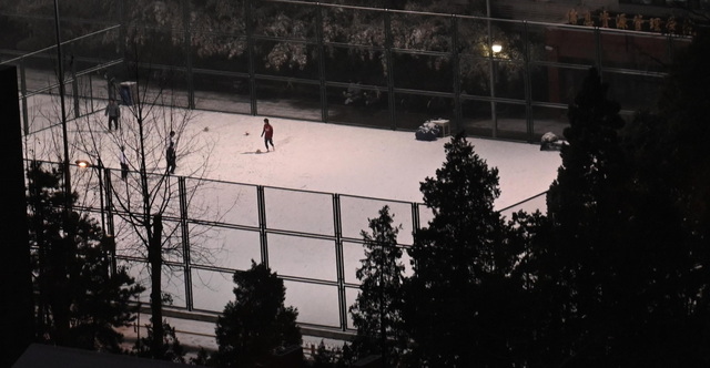 附近大学的操场上，有人冒雪踢球